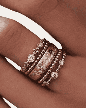 Close-up of a hand wearing multiple bronze rings with gemstones on a white background