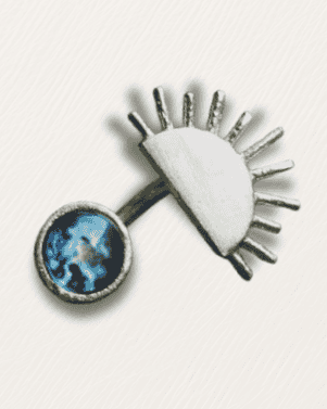 Decorative brooch with eye design and blue gemstone on a white background