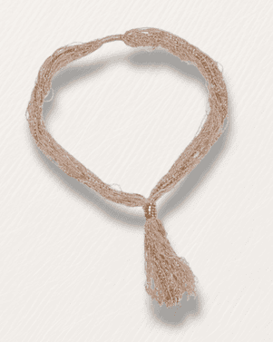 Beige knitted headband with tassel on a light gray background