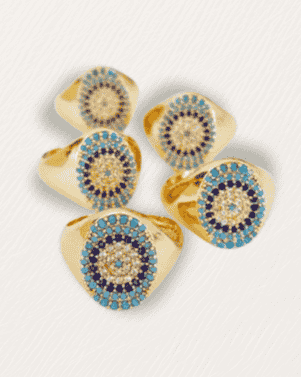 Set of gold rings with blue and purple gemstones on a light gray background