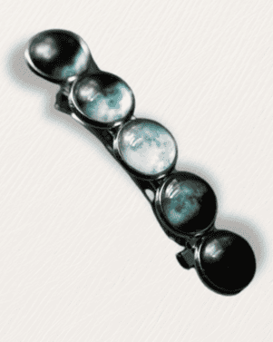 Black hair clip with round silver and black stones on a white background