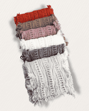 Stack of knitted scarves in various colors on a white background