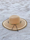 Beige straw hat with a decorative band on a sandy surface