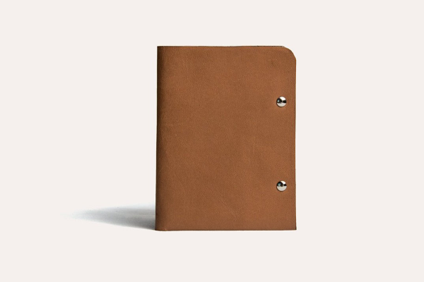Brown leather notebook with metal rings on a light gray background