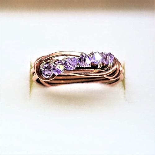 Rose gold ring with purple gemstones on a light background