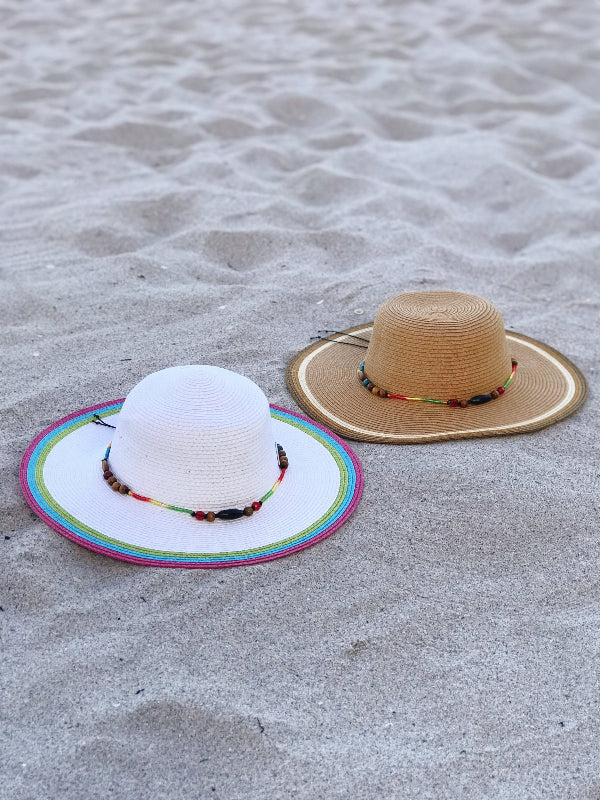 White wide‑brim striped beach hat with multicolor beaded band on sand