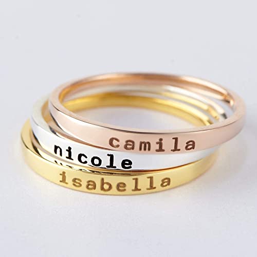 Stack of three rings with engraved names on a light gray background