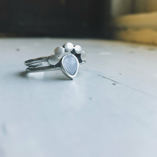 Silver ring with a blue gemstone on a light gray surface