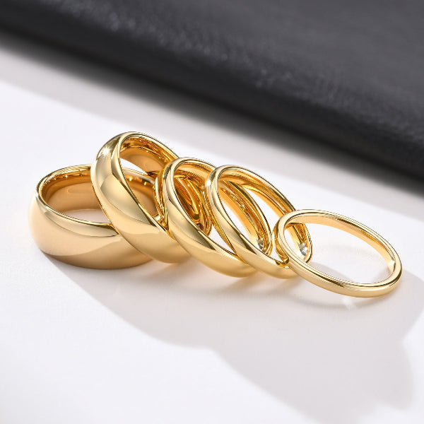 Set of gold rings on a white surface with a black fabric background
