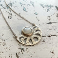 Silver necklace with a circular pendant on a textured surface