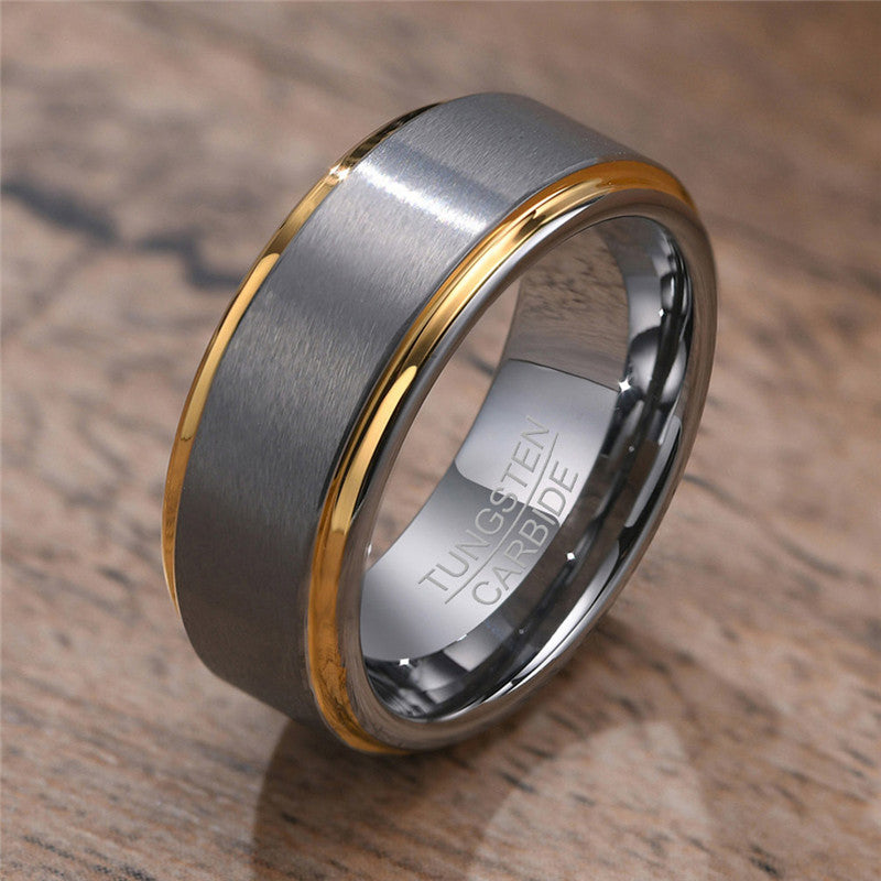Tungsten carbide ring with gold inlay on a wooden surface
