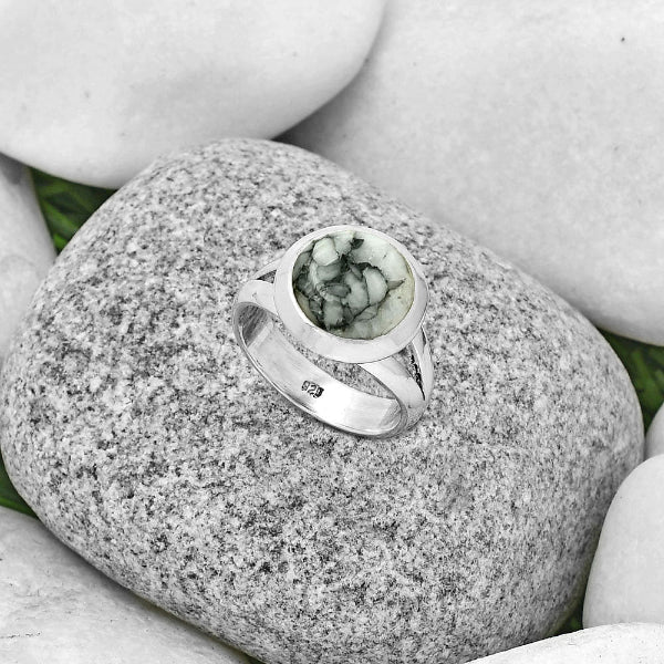 Silver ring with a green stone on a rock