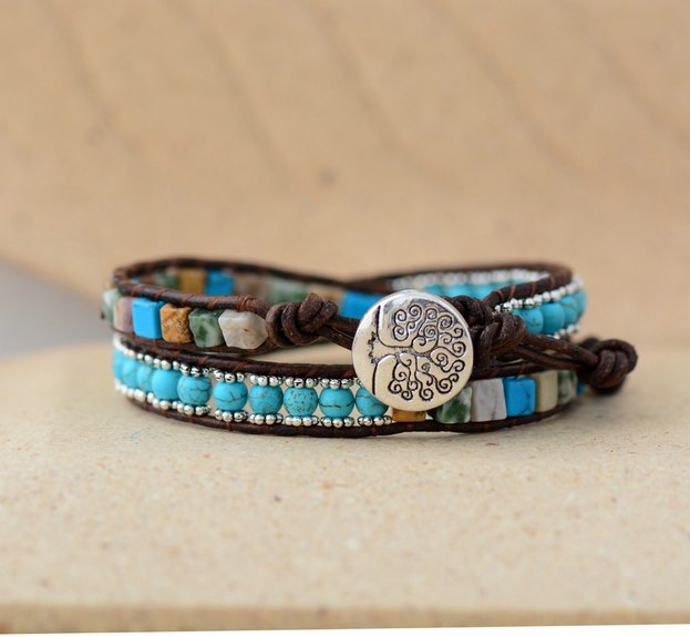 Multistrand bracelet with turquoise beads and a silver charm on a beige surface