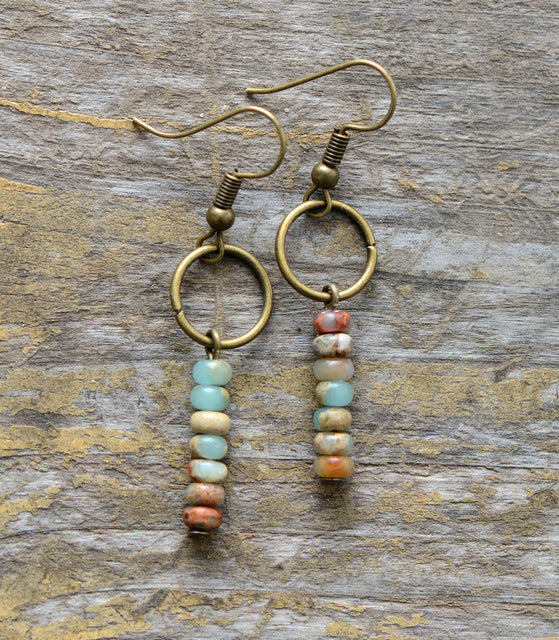 Pair of earrings with gold rings and bead drops on a wooden surface