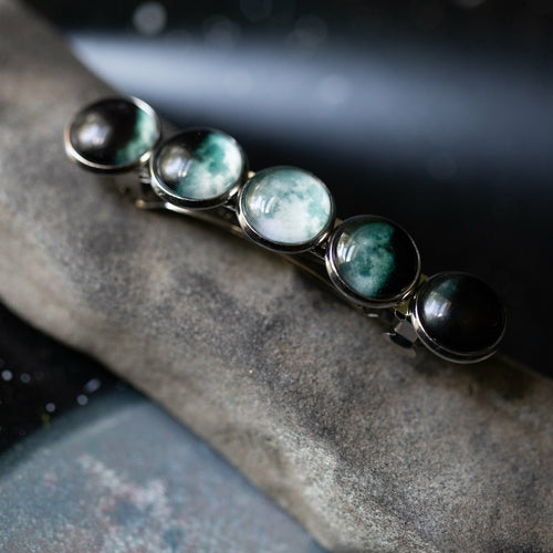Bracelet with green and black gemstones on a stone surface