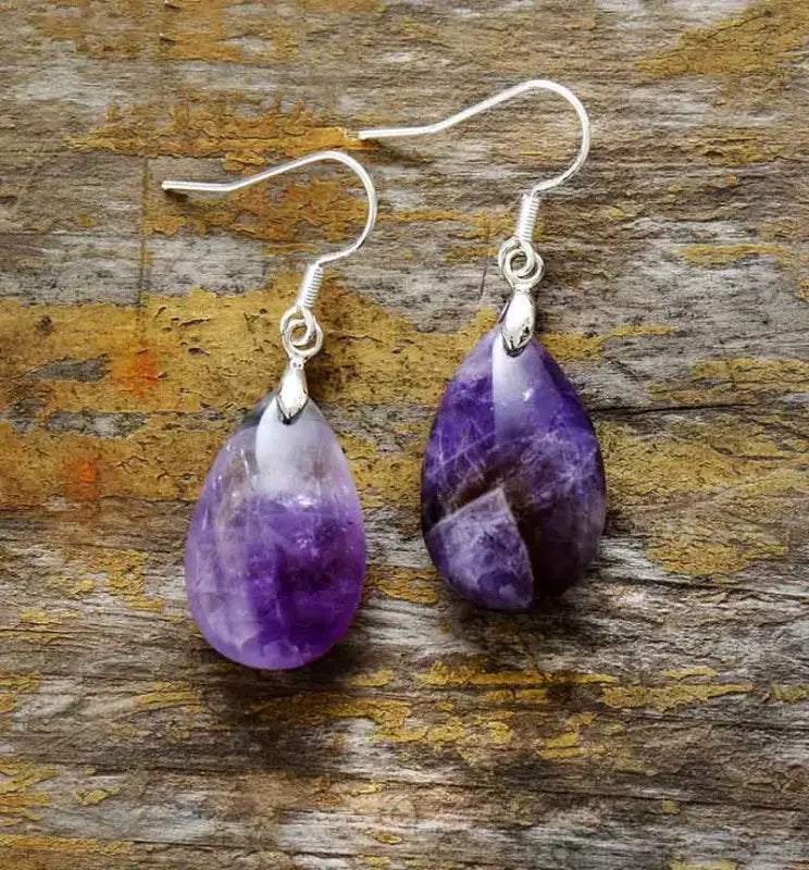 Pair of purple teardrop earrings on a wooden surface