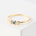 Gold ring with three gemstones on a light background