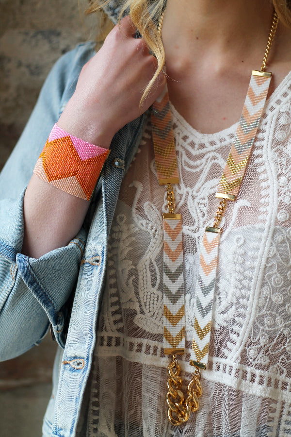 Person wearing a colorful necklace with geometric patterns and a matching bracelet.