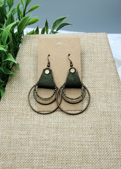 Pair of earrings on a beige card with a green leafy background