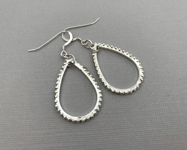 Silver hoop earrings on a gray background