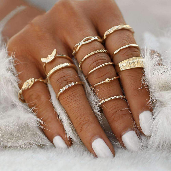 Hand wearing multiple gold rings on a white fur background