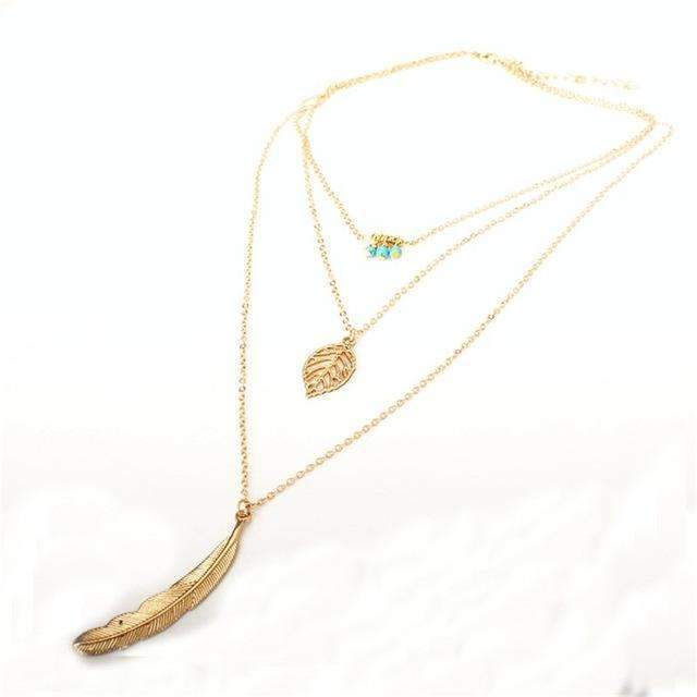Gold necklace with feather pendant on a white background