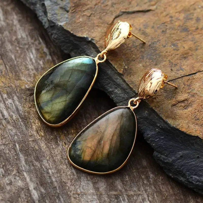 Gold-framed labradorite earrings on a stone surface