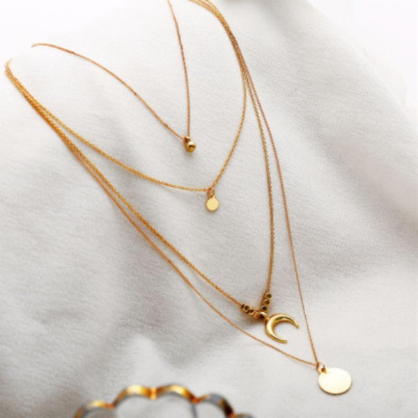 Gold necklaces with various pendants on a light gray background