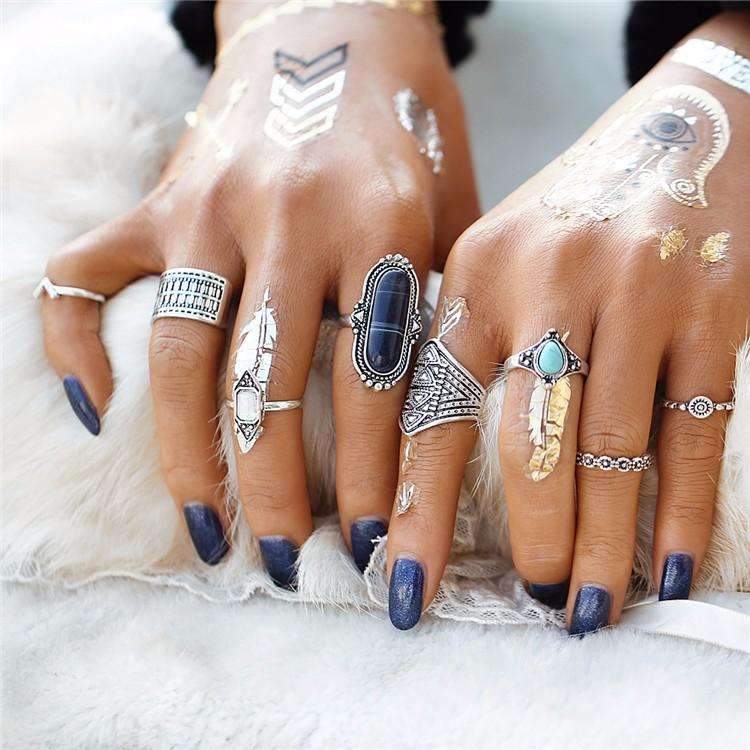 Close-up of hands with multiple rings and blue nail polish on a white background