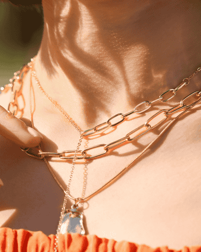 lady in orange dress wearing chic, modern boho chains and gold pendant 