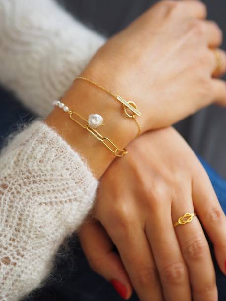 woman wearing luxury gold chain bracelets with pearls