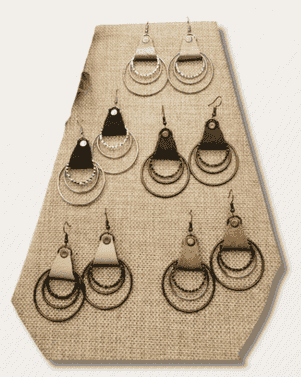 Set of earrings displayed on a beige hexagonal earring stand.