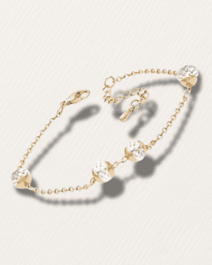 Gold bracelet with clear gemstones on a light gray background