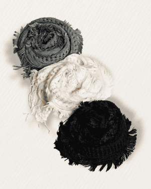 Three knitted balls in gray, white, and black on a light background