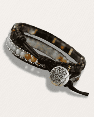 Bracelet with leather strap, beads, and decorative clasp on a white background