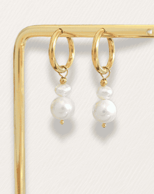 Gold hoop earrings with white pearls on a gold stand against a white background