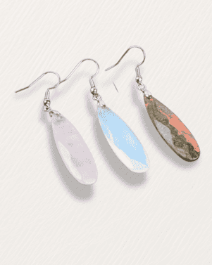 Set of three earrings with different colored stones on a white background