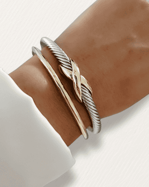 Silver cable cuff bracelet on a wrist with a white background