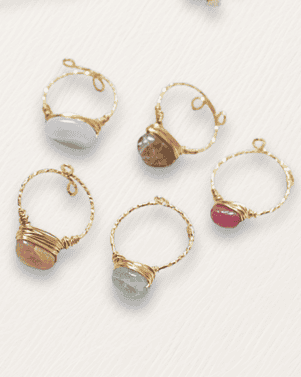 Set of gold-rimmed rings with various gemstones on a white background