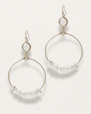 Gold hoop earrings with small stones on a light gray background
