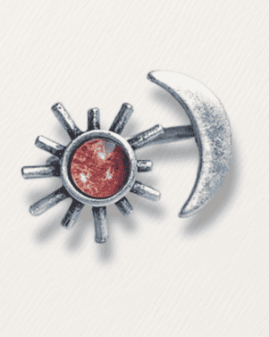 Silver sun and moon charm with red gemstone on a white background
