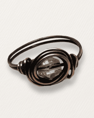 Bronze wire-wrapped ring with a clear gemstone on a white background