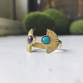 Pair of gold rings with gemstones on a white surface