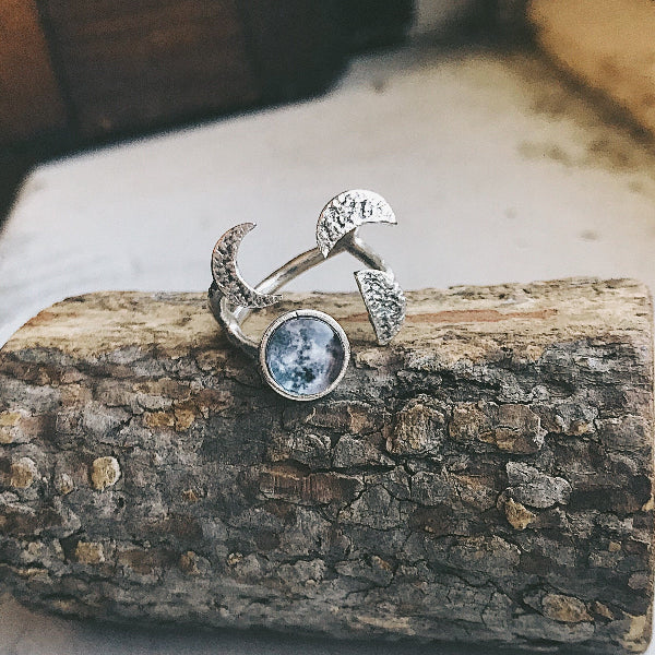 Silver ring with moon and star design on a wooden surface