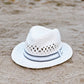White straw hat with a black band on a sandy beach