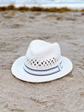 White straw hat with a black band on a sandy beach