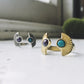 Two pairs of earrings, one gold and one silver, with gemstones on a white surface.