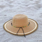 Beige straw hat with a decorative band on a sandy surface