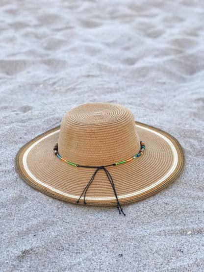 Beige straw hat with a decorative band on a sandy surface