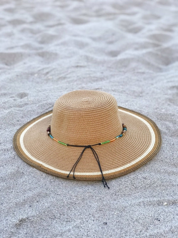 Beige straw hat with a decorative band on a sandy surface